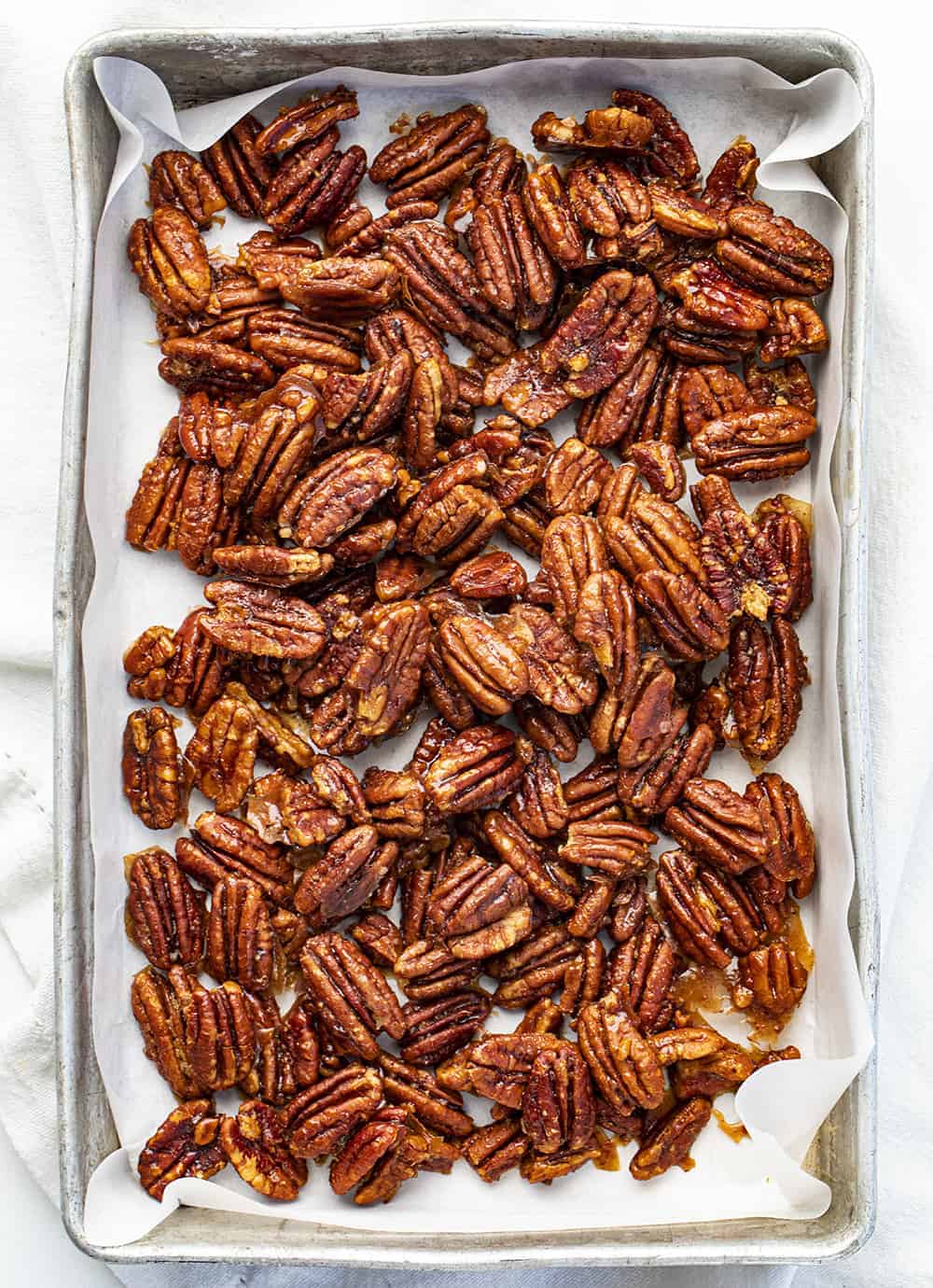 Candied Pecans are a sweet and crunchy treat that is easy to mix together and bake anytime you need to satisfy a sweet tooth! Candied Pecans, How to Make Shiney Candied Pecans, Perfect Candied Pecans, iambaker, i am baker, recipes, Christmas, baking, holidays, appetizer Overhead of Candied Pecans in a Pan