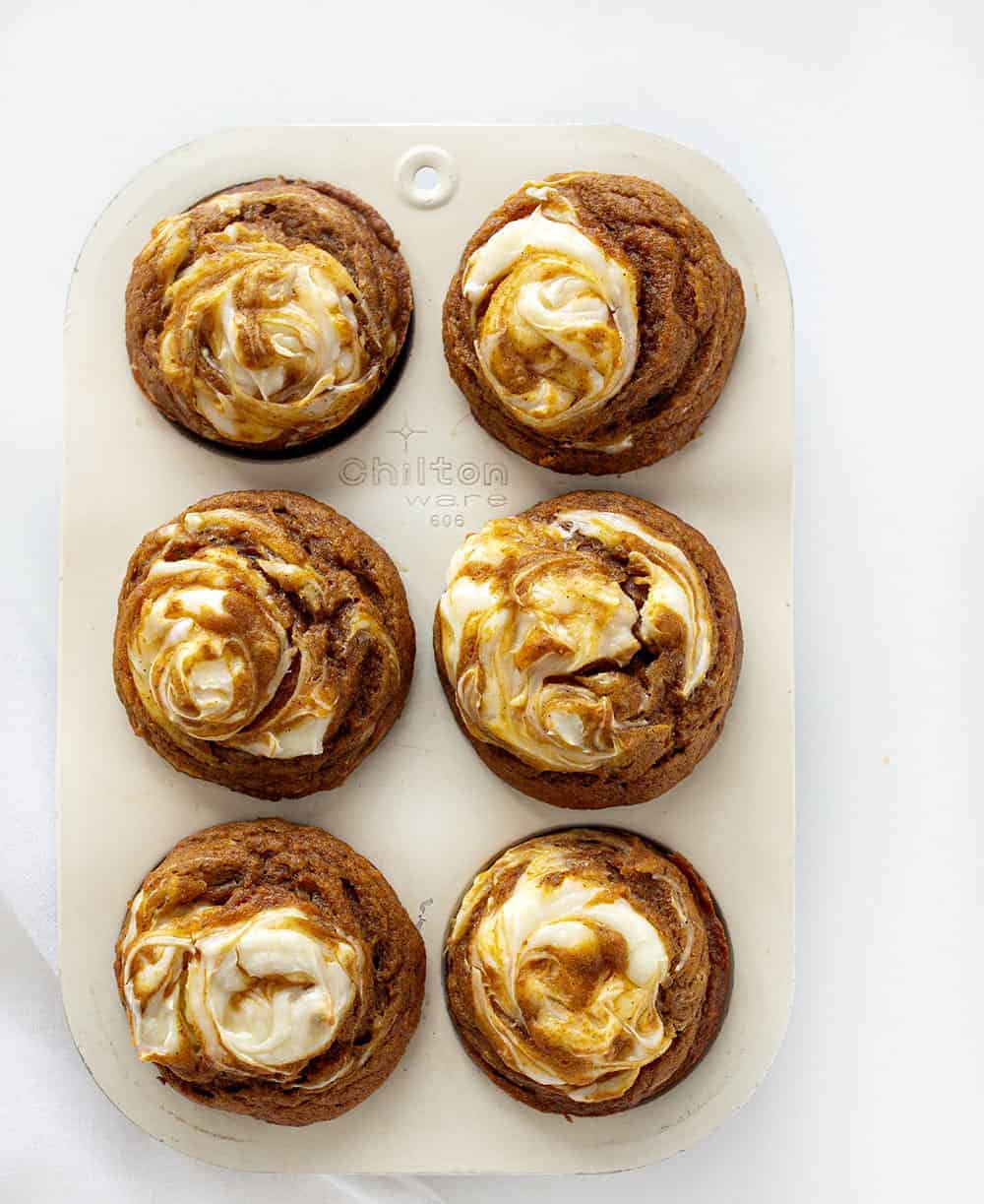 With a cream cheese swirl and a perfectly moist pumpkin muffin, Pumpkin Cream Cheese Swirl Muffins are the best thing about pumpkin spice season! #pumpkincreamcheeseswirlmuffins #muffinrecipes #pumpkinmuffins #iambaker #homemadepumpkinspice #pumpkinspice #baking #desserts #creamcheesefilledmuffins Pan of Pumpkin Cream Cheese Muffins Recipe